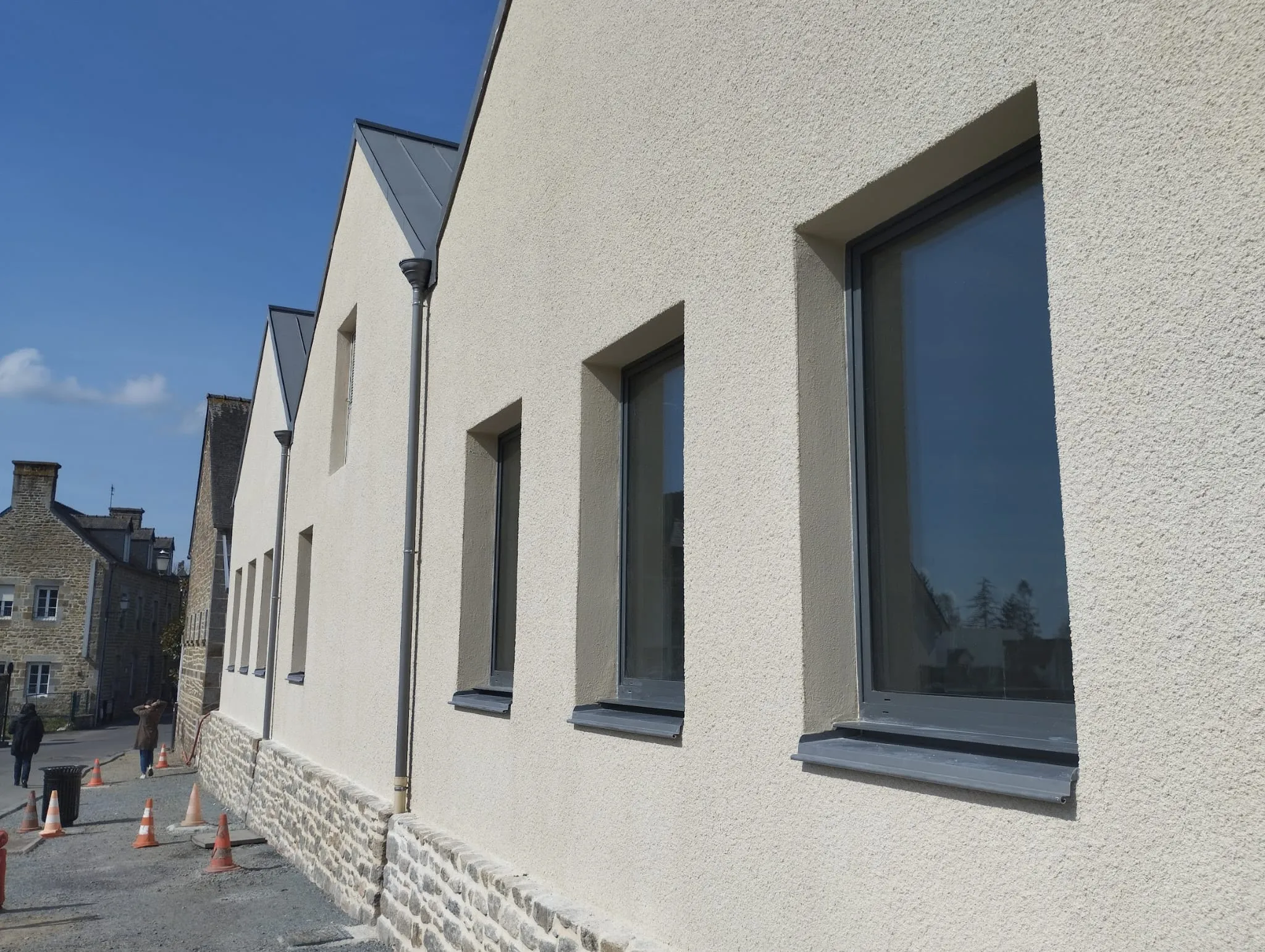 Façade enduite sur bâtiment neuf, soubassement en pierre